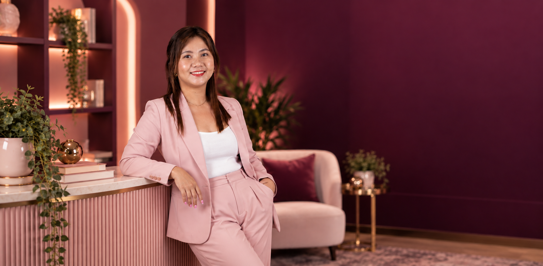 Camille in a pink suit in a warm pink studio