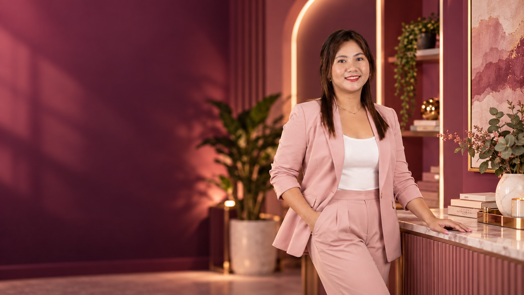 Camille in a pink suit standing in a pink studio
